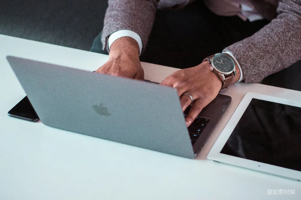 高清摄影  男人在iPad和iPhone之间使用MacBook