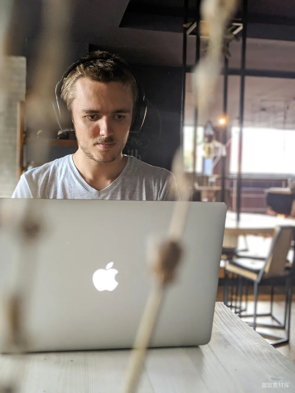 高清摄影  穿着灰色V领衬衫的男人站在苹果MacBook面前。