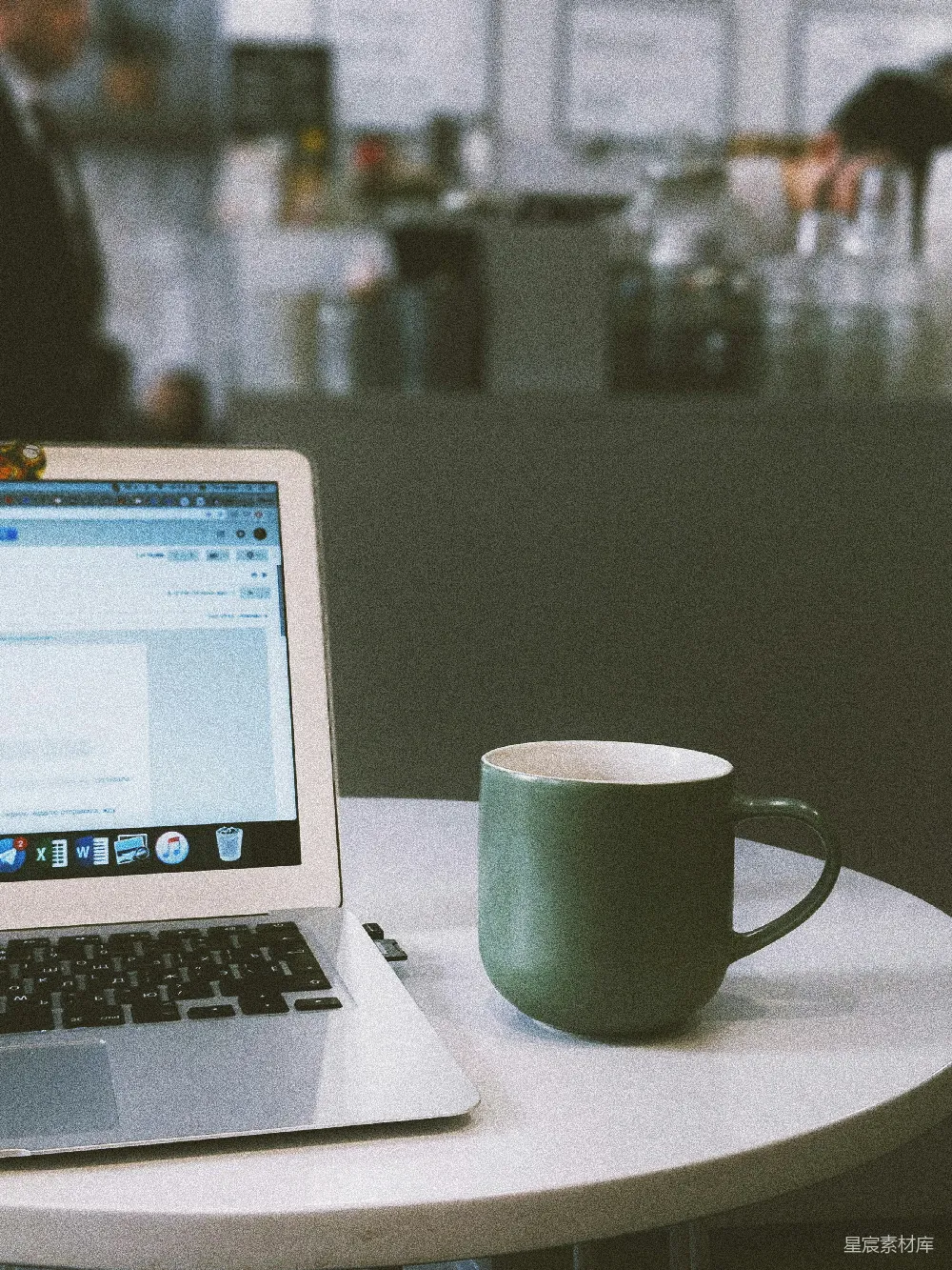 高清摄影  绿色的马克杯放在MacBook旁边。
