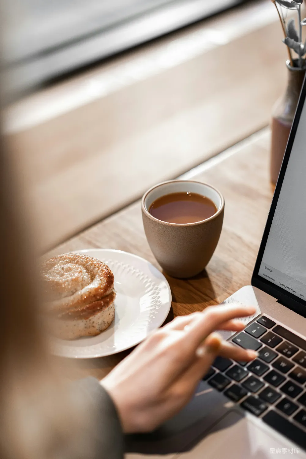 高清摄影  使用MacBook Pro的那个人旁边有一个白色的陶瓷杯，杯子里装有棕色的液体。