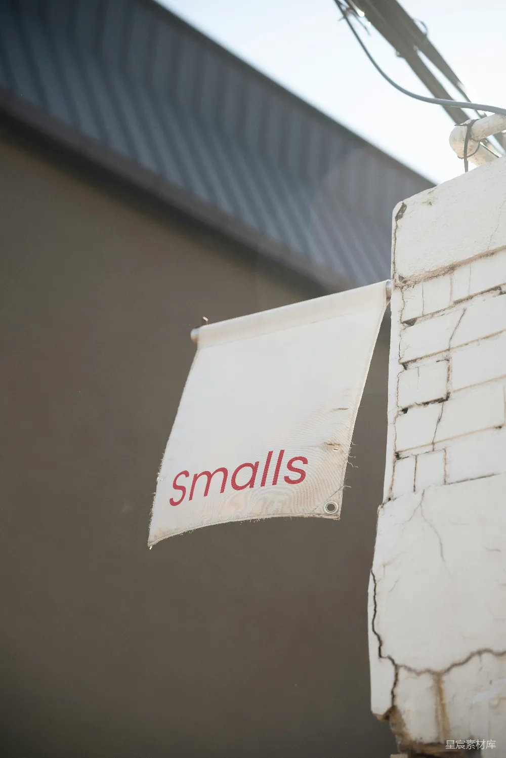 高清摄影  一个白色的“smalls”标志悬挂在砖柱上。