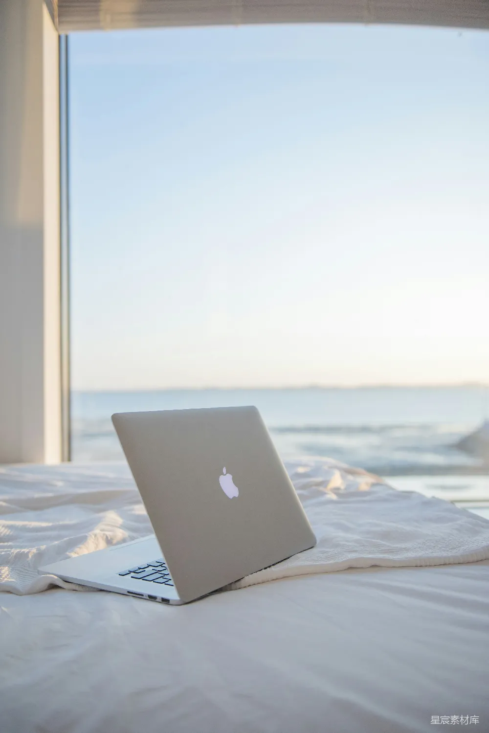 高清摄影  银色的MacBook放在白色床上
