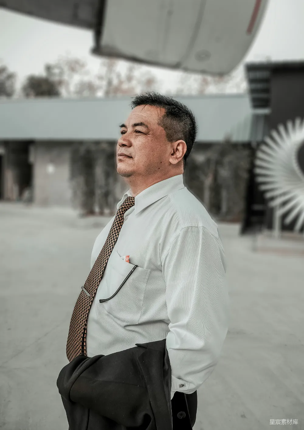 高清摄影  一位穿着衬衫和领带的男人站在一座建筑物前。