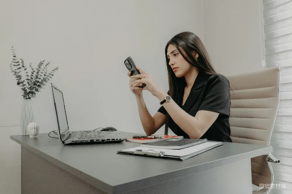 高清摄影  一位女士正在办公桌前使用手机。