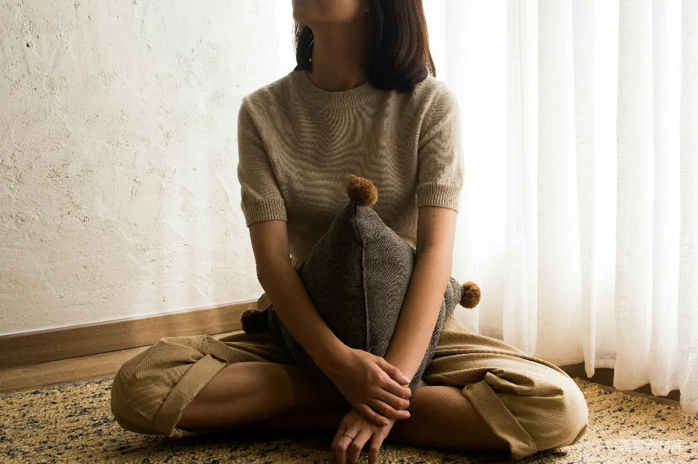 高清摄影  穿着白色针织毛衣的女人坐在棕色木制椅子上。