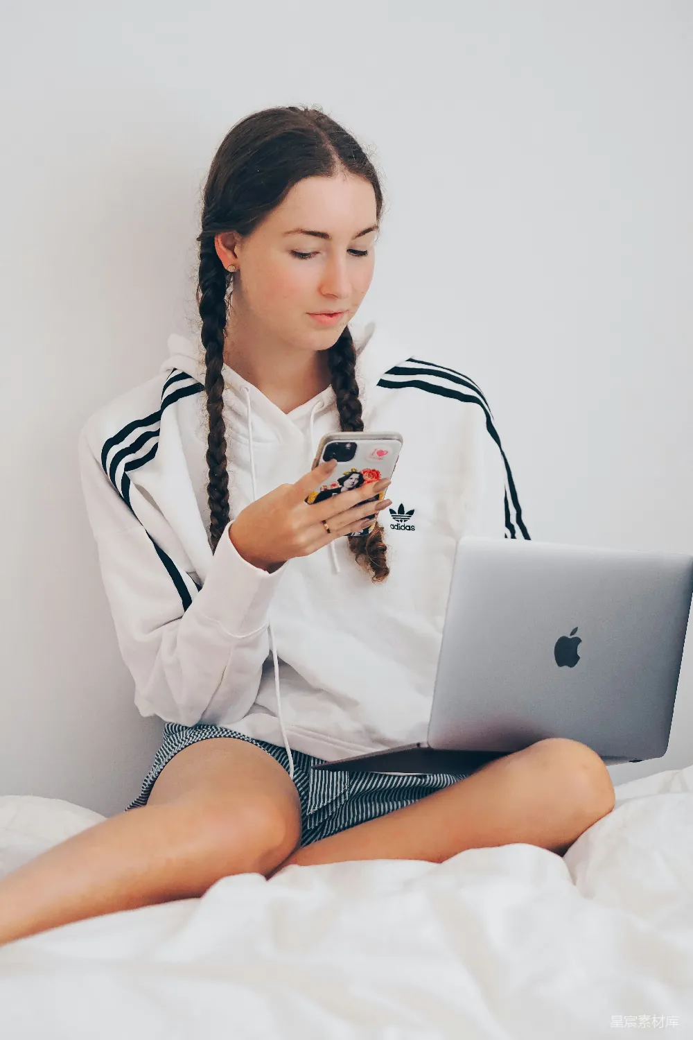 高清摄影  穿白大褂的女士坐在床上使用银色的MacBook。