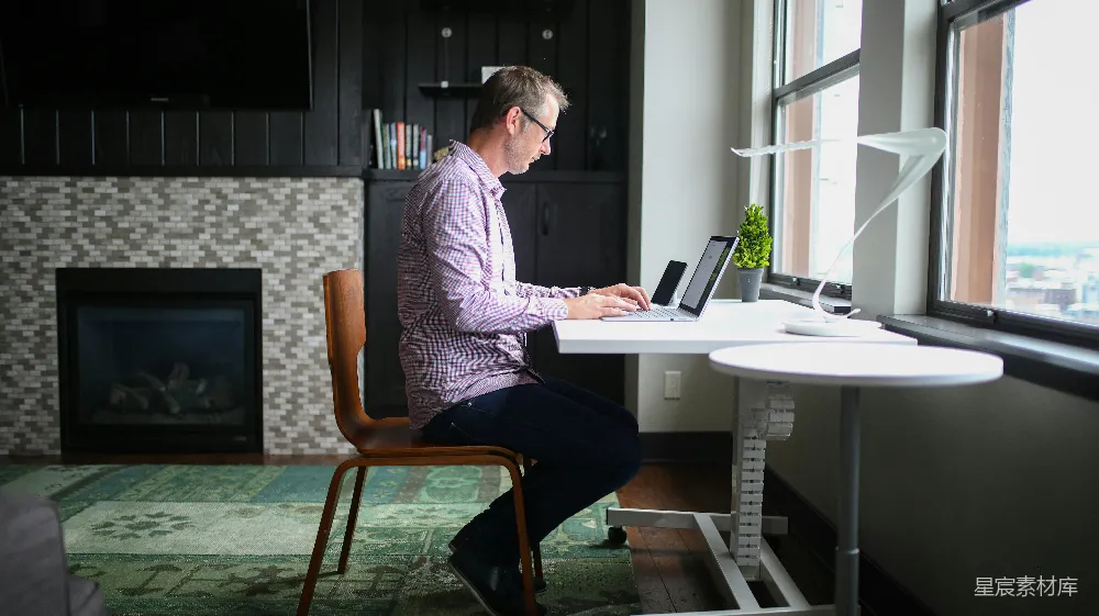 高清摄影  穿着灰色衬衫的男人坐在棕色木椅上使用MacBook Pro。