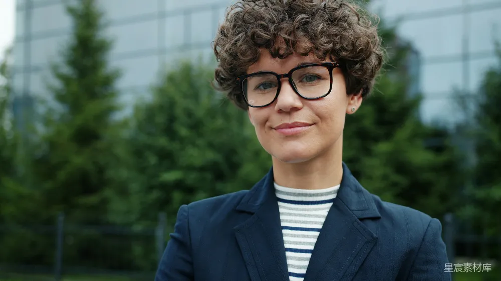 高清摄影  一个有着卷发和戴眼镜的女人微笑着。