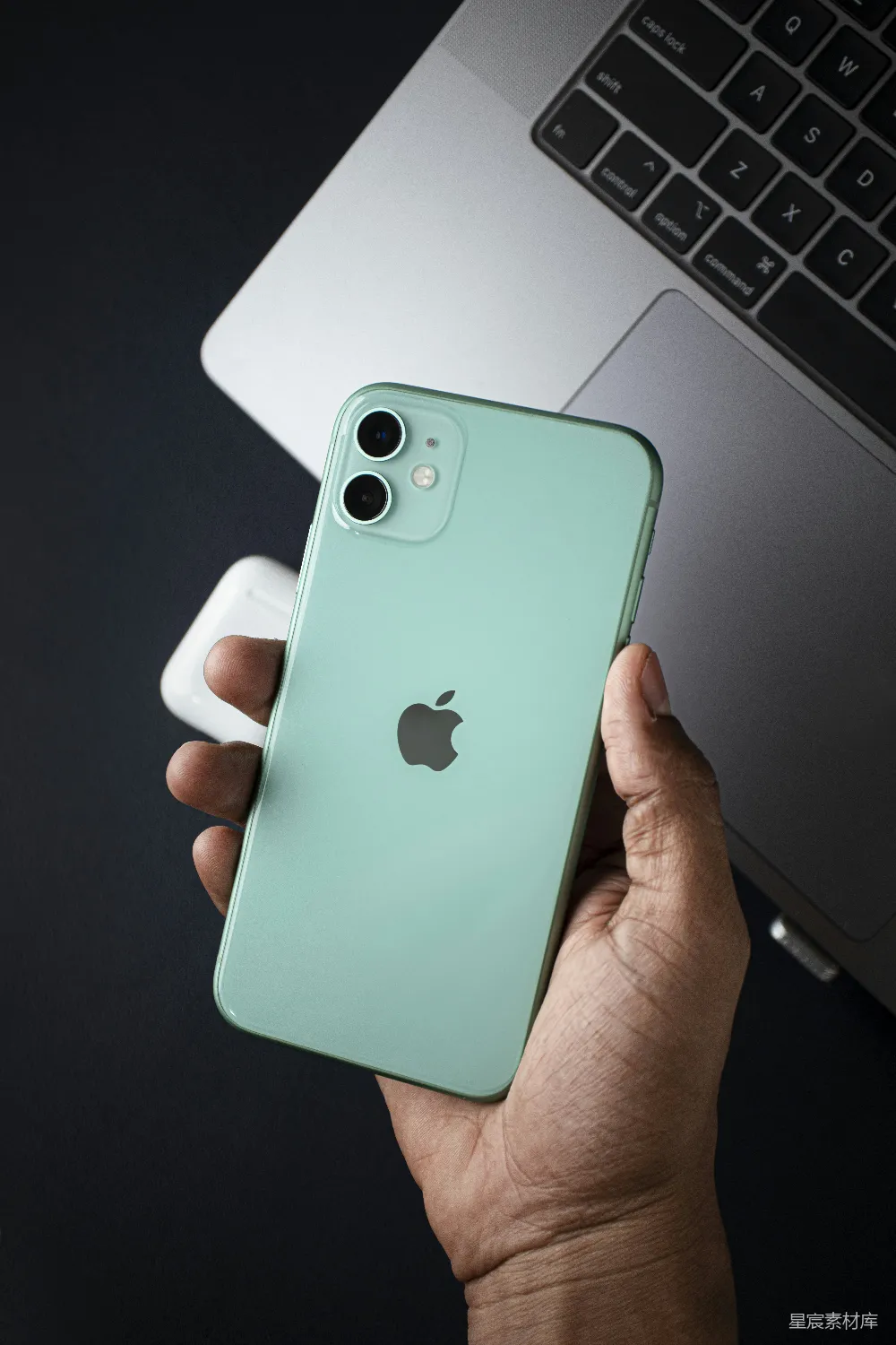 高清摄影 壁纸 一个人拿着一部iPhone，放在一台笔记本电脑前面。