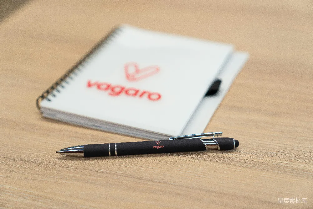 高清摄影  一支带Vagaro标志的笔和记事本放在木制表面上。