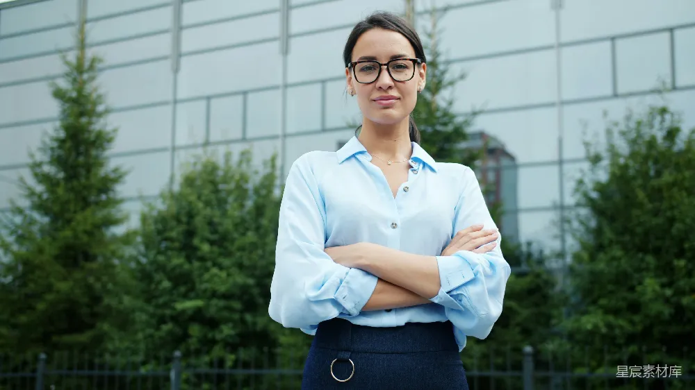 高清摄影  戴眼镜的女士在户外交叉双臂站着。
