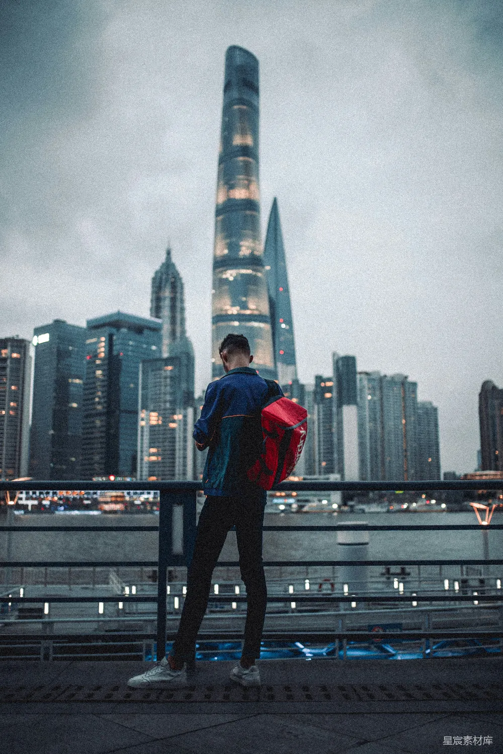 高清摄影  穿着红色连帽衫和黑色裤子的男人站在黑色金属栏杆上。