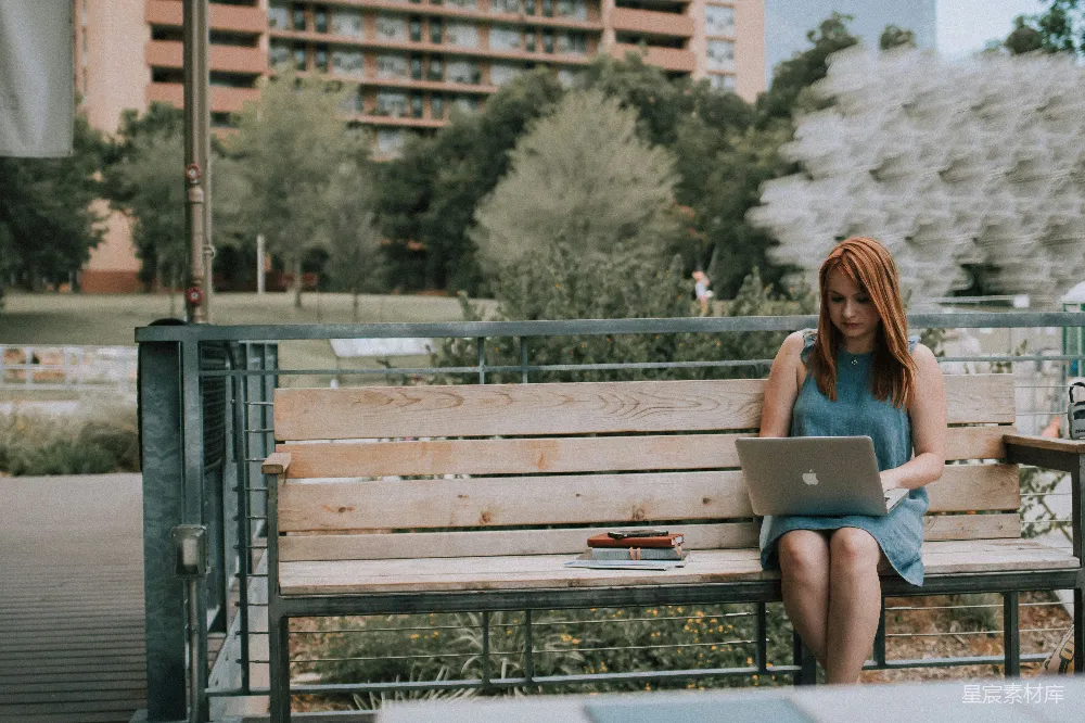 高清摄影  坐在长椅上的白人女性正在使用MacBook Pro。