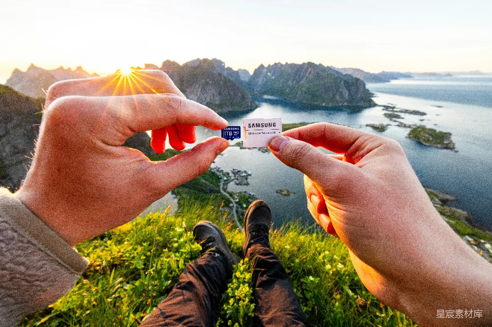 高清摄影  双手拿着SD卡，背景是风景如画的山海景色。