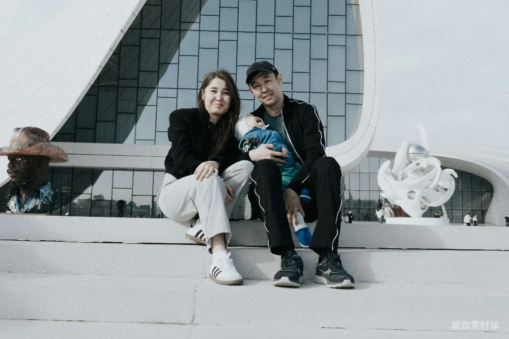 高清摄影  一对抱着婴儿的夫妇坐在现代建筑前