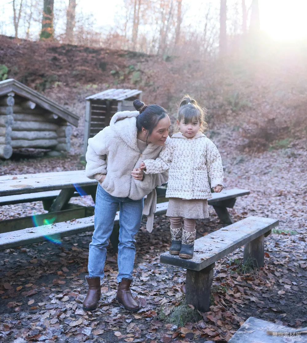 高清摄影  一对母子在树林中的野餐长椅上。