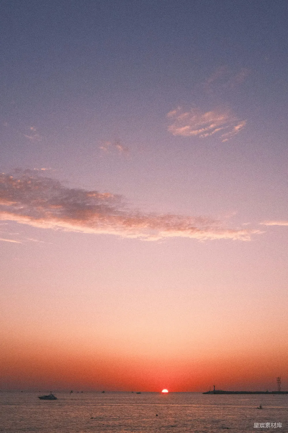高清摄影  夕阳正在海洋上落下，水面上有船。