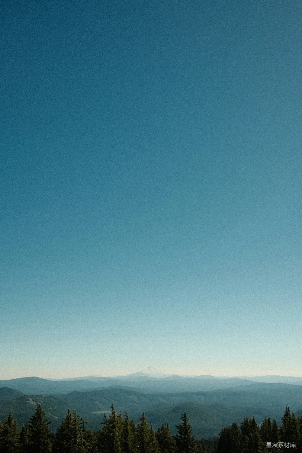 高清摄影  一幅远处有树林和山脉的山脉景观图。
