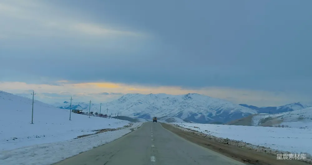 高清摄影  一条道路，背景是被雪覆盖的山脉。