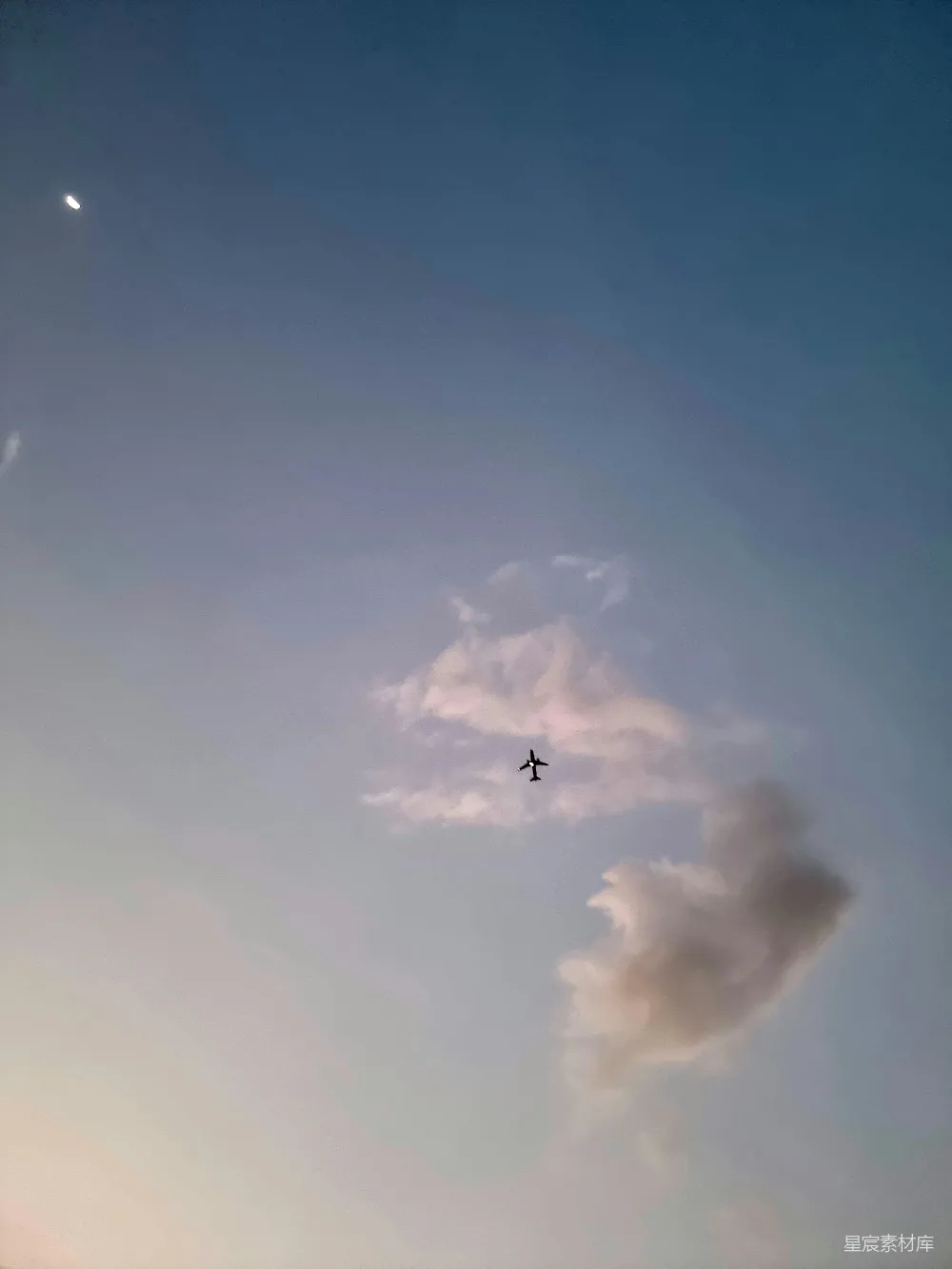 高清摄影  一架飞机在天空中飞行，背景中有月亮。