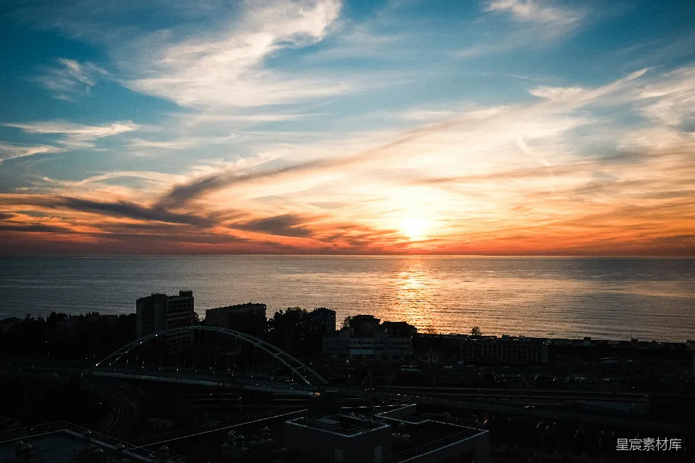 高清摄影  夕阳正悬挂在海边的城市上空。