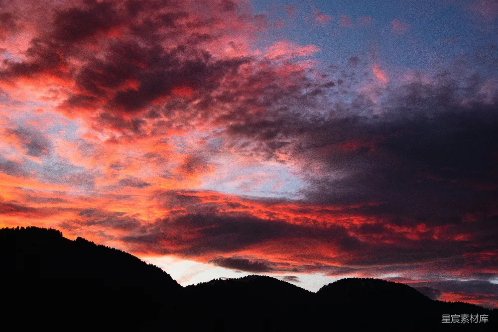 高清摄影  鲜艳的红色和橙色夕阳云层在黑暗的山影上。
