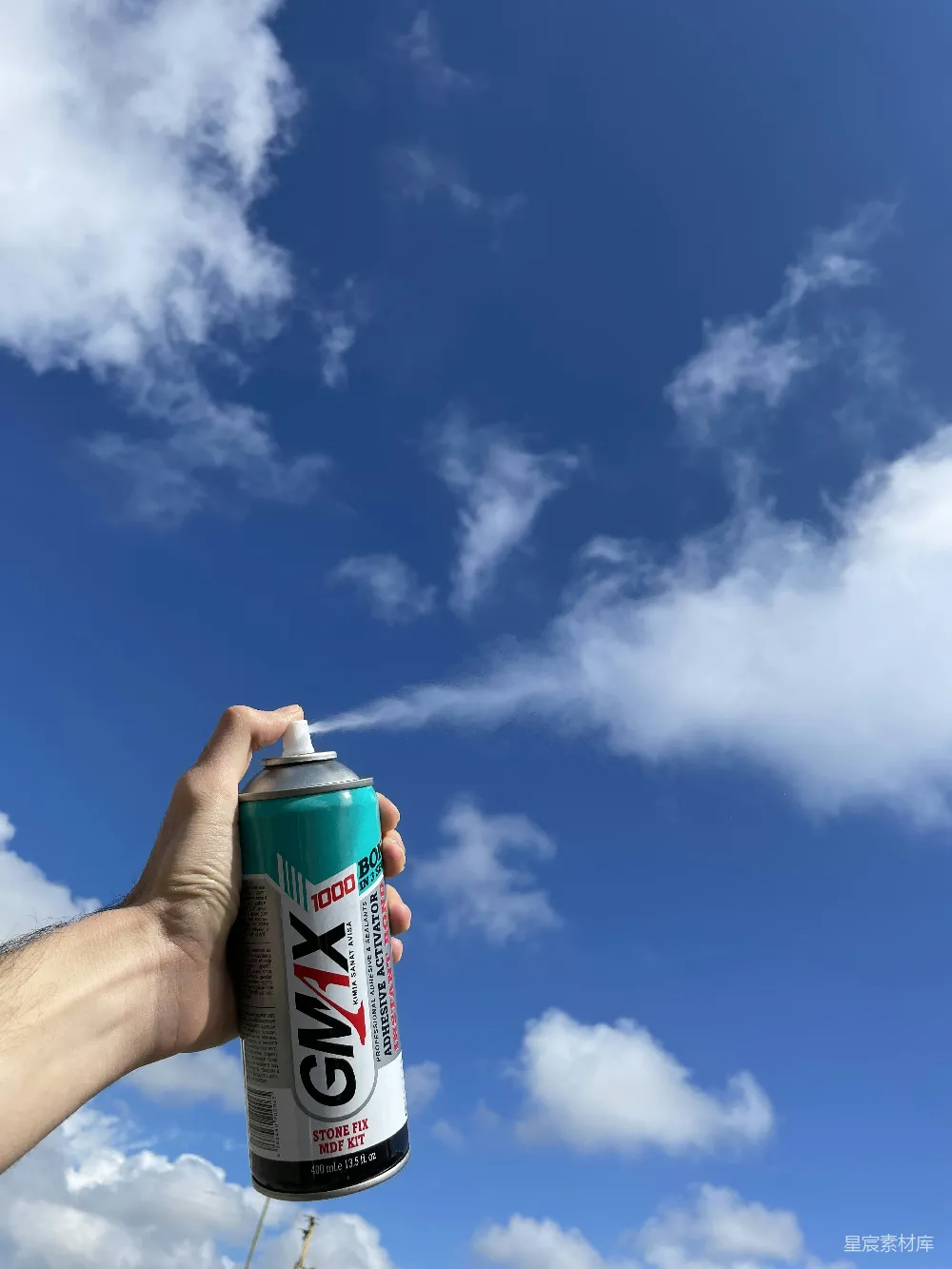 高清摄影  手持绿色和白色喷漆罐的人在白天蓝天下白云间