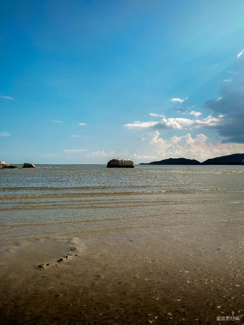高清摄影  一个有沙子的海滩，背景中有一片水域。