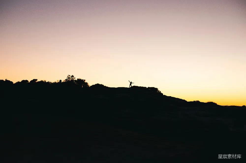 高清摄影  一个人站在山顶上，夕阳西下。