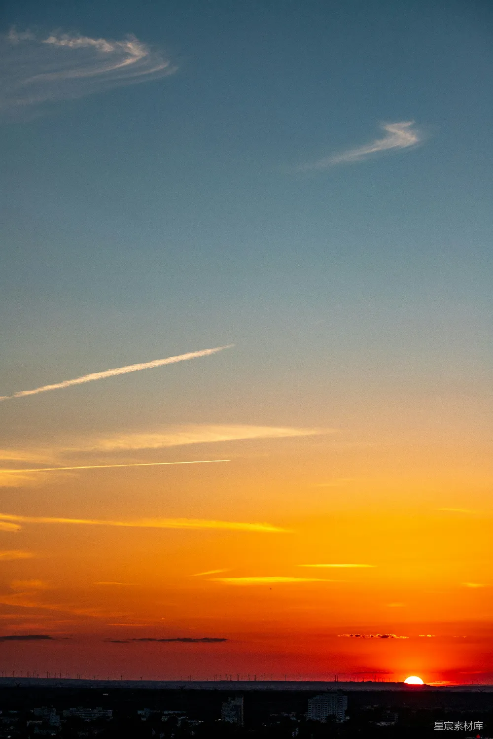 高清摄影  城市天际线上方绚丽的夕阳天空，空中有航迹。