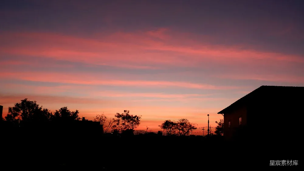 高清摄影  夕阳西下，天空色彩斑斓，树木剪影与房屋交织。