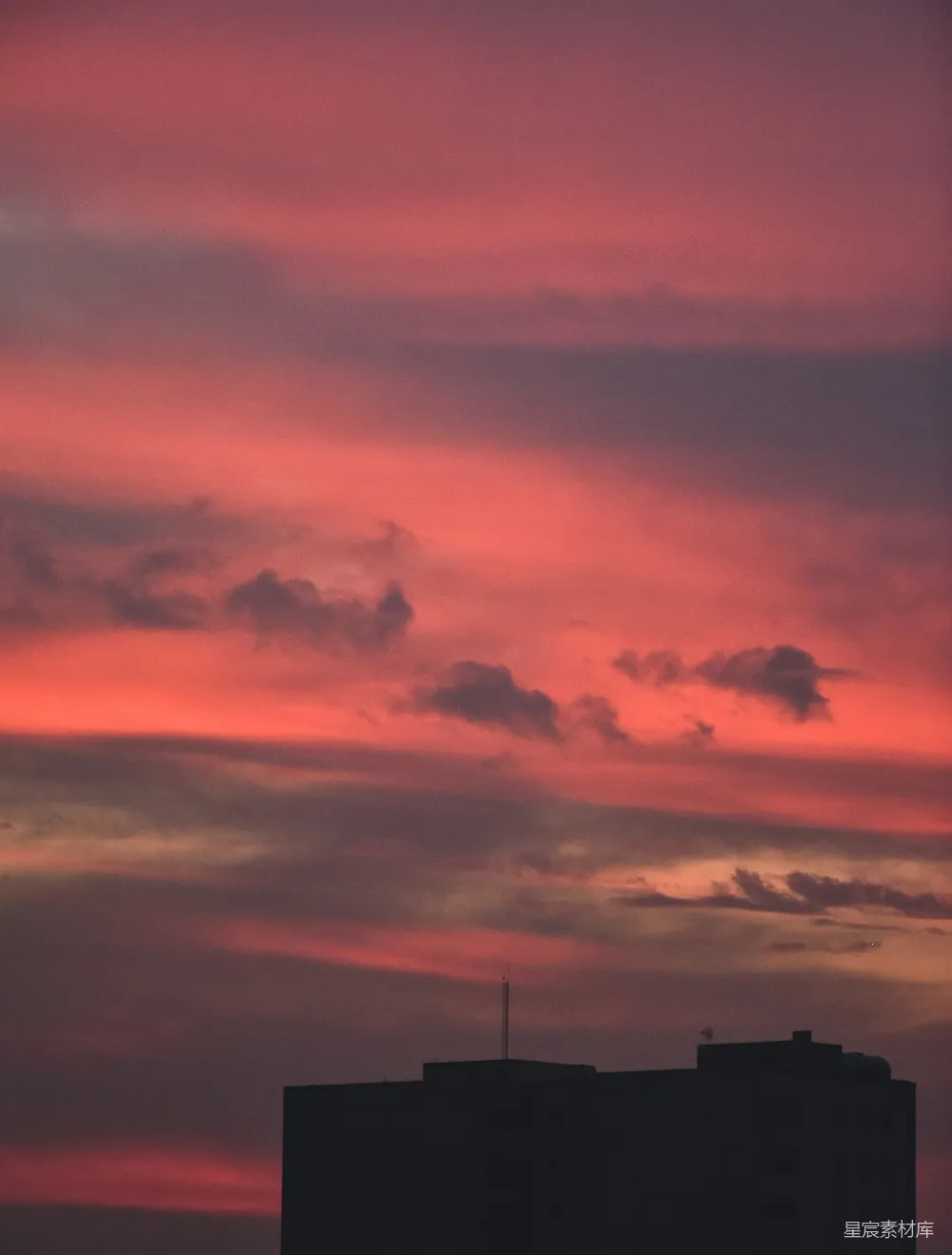 高清摄影 壁纸 天空呈现红色和粉色，前景中有一栋建筑物。