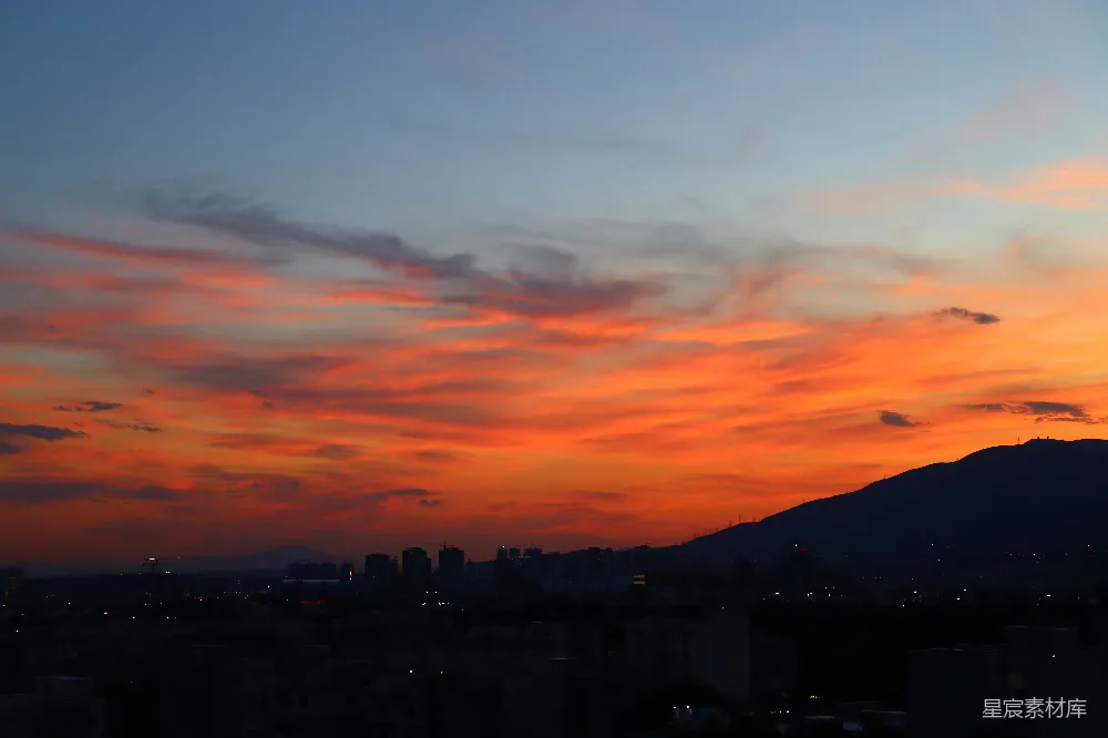 高清摄影  城市日落景色，背景中有一座山。