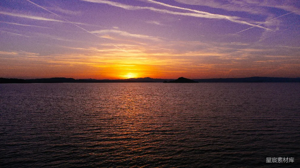 高清摄影 自然 夕阳映照在水面上，天空中有飞机尾迹。
