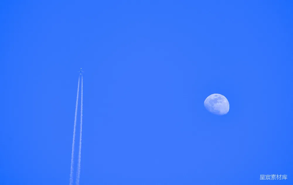 高清摄影  一架飞机在空中飞行，背景中有月亮。