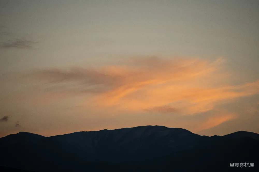 高清摄影  山峰在柔和的橙色夕阳天空下剪影