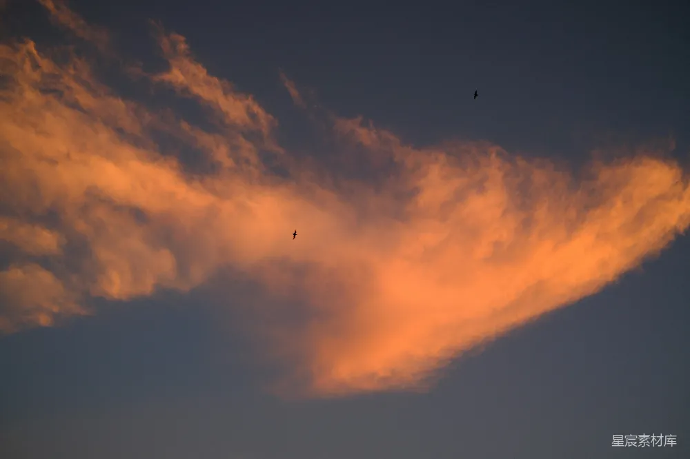高清摄影  夕阳的余晖照亮橙色的云朵，与黑暗的天空形成鲜明对比。