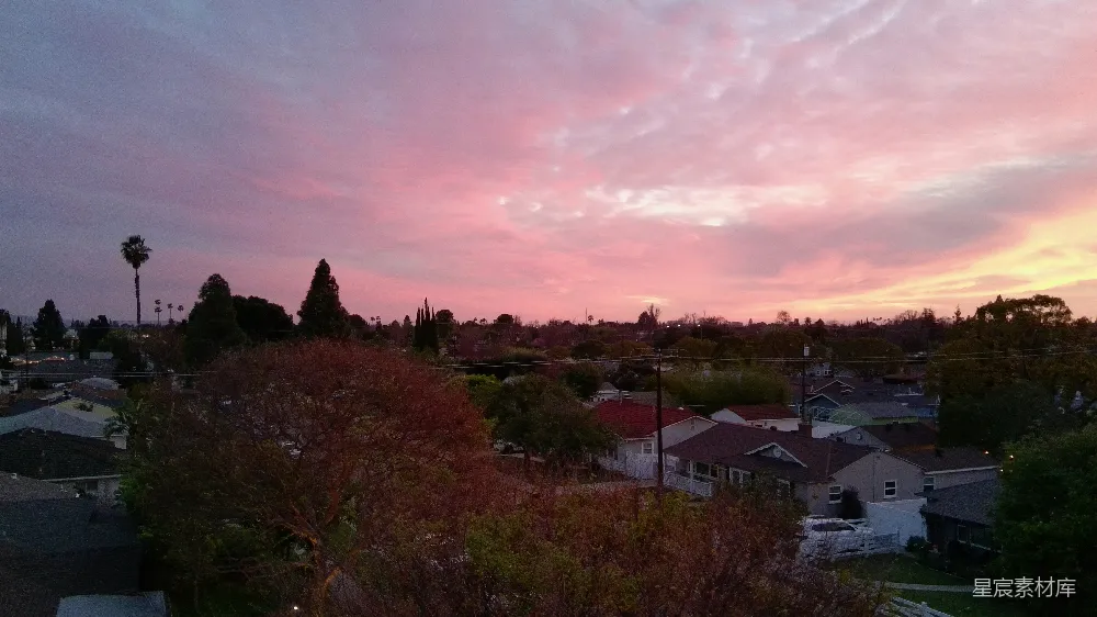 高清摄影  粉色和橙色的夕阳映照在郊区屋顶上。
