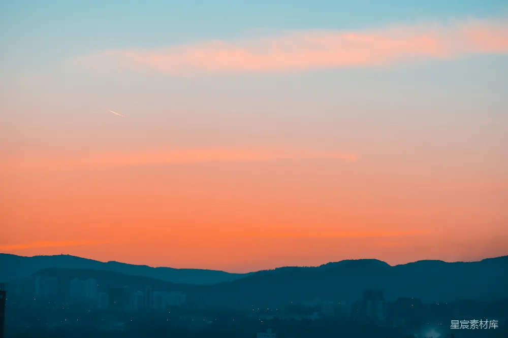 高清摄影  夕阳西下，天空灿烂，山峦在夜色中显得深邃，城市灯火在下方闪烁。