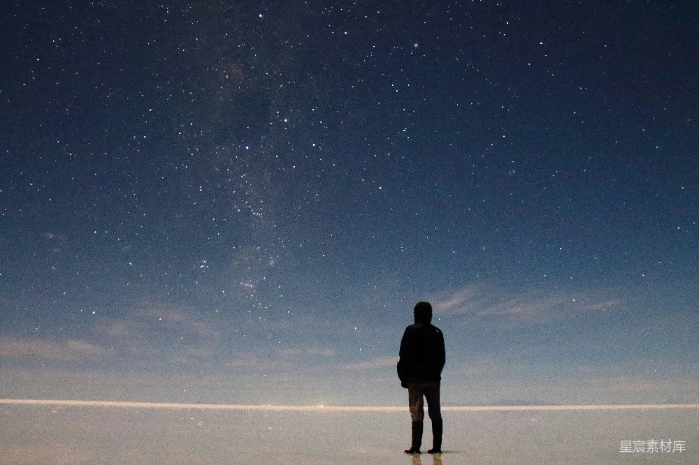高清摄影  一个男人站在田野里，天空中有星星。