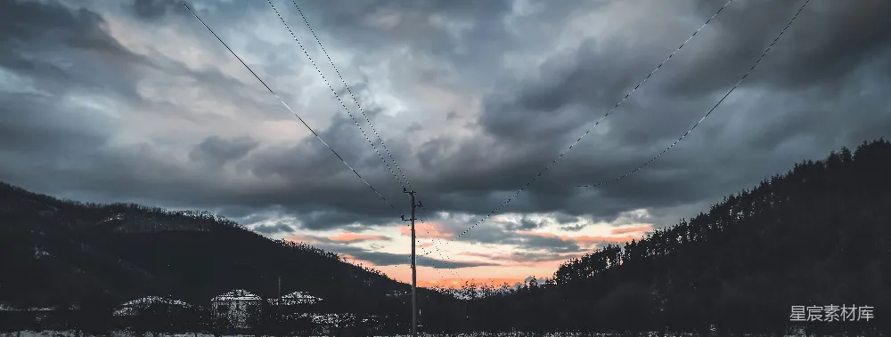 高清摄影  一座山上空云雾缭绕，前景中有一根电线杆。