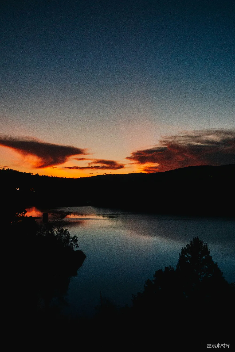 高清摄影  一片有树木和夕阳背景的水域。