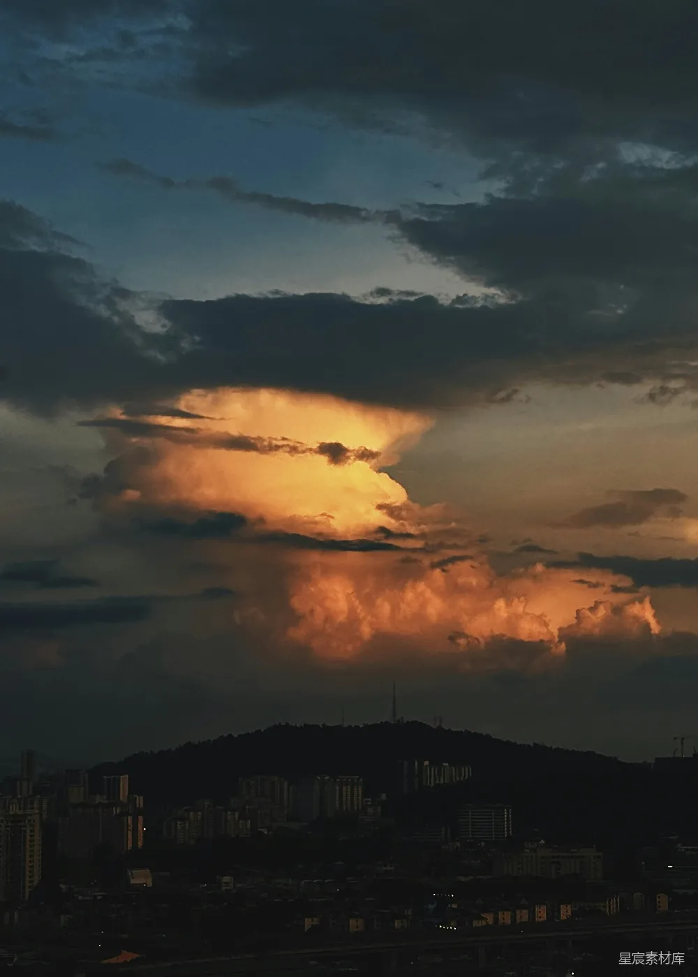 高清摄影  夕阳在城市上空落下，背景中有一座山。