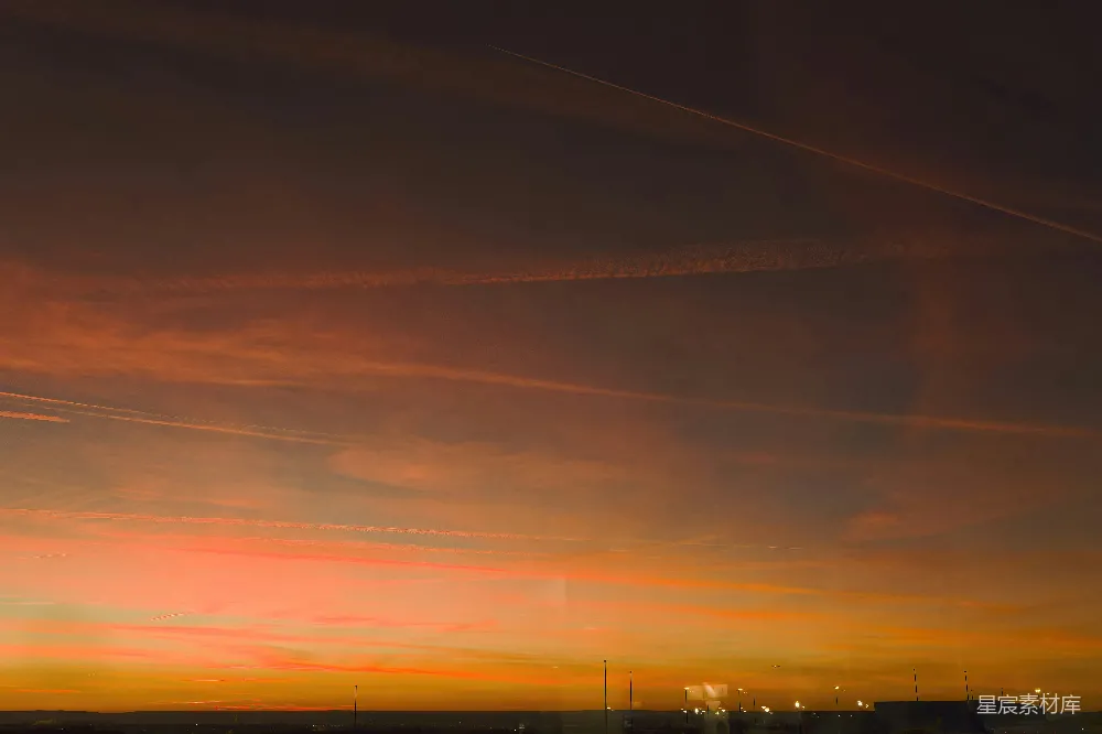 高清摄影  夕阳西下，远处灯光映衬着飞机尾迹。