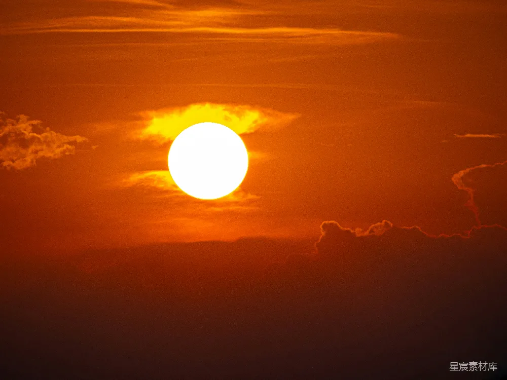 高清摄影  夕阳在橙色的天空中落下，云朵飘过。