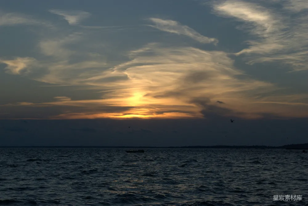 高清摄影  在多云的天空下，夕阳下的水面