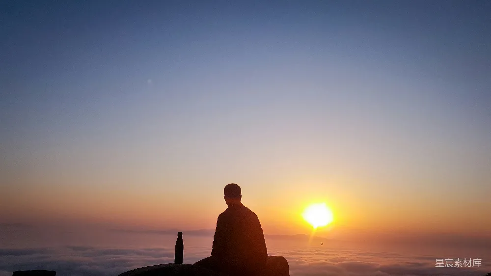 高清摄影  夕阳下，一个人坐在岩石上的剪影