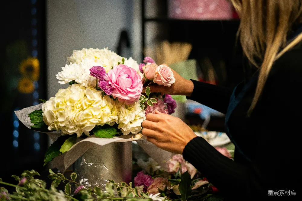 高清摄影  一位女士正在桌子上将花插在花瓶里。