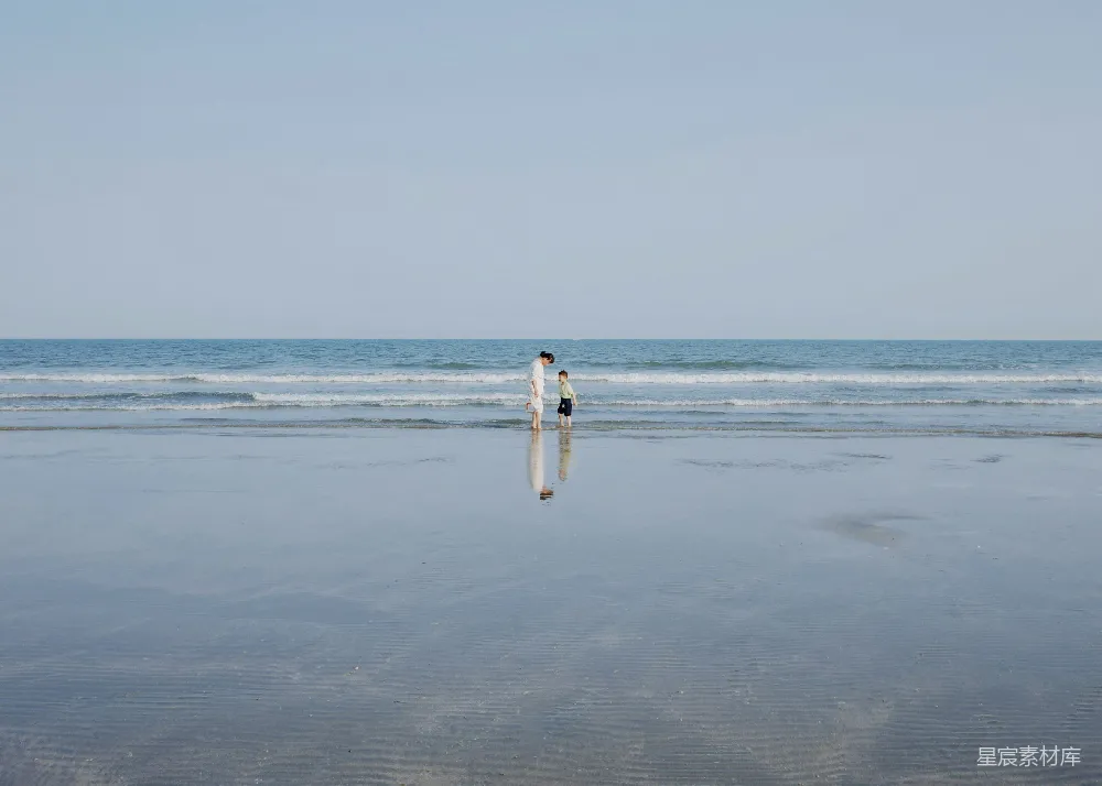 高清摄影  人们沿着海滩朝向大海走去。