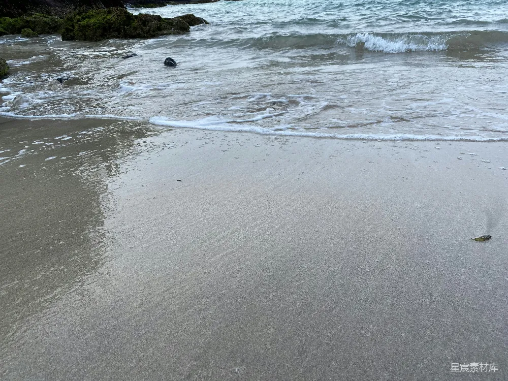 高清摄影  一个沙滩，海浪拍打着岸边。